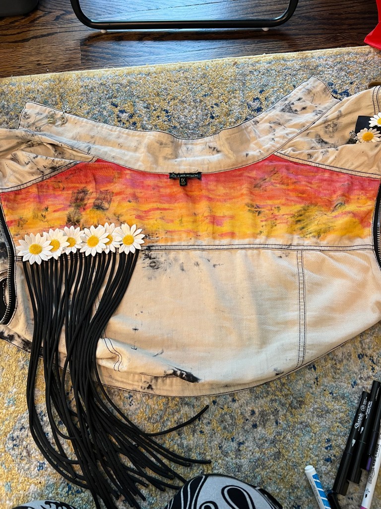 An in-progress DIY vest with daisies and paint